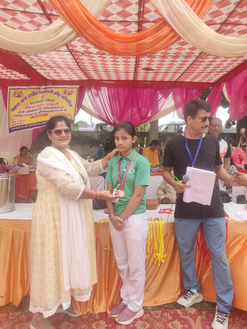 Student being felicitated with a medal by an officer at a district sports event