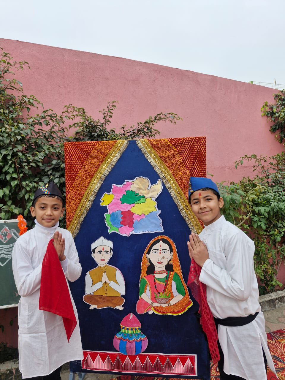 Students in traditional attire showcasing a hand-painted cultural art display